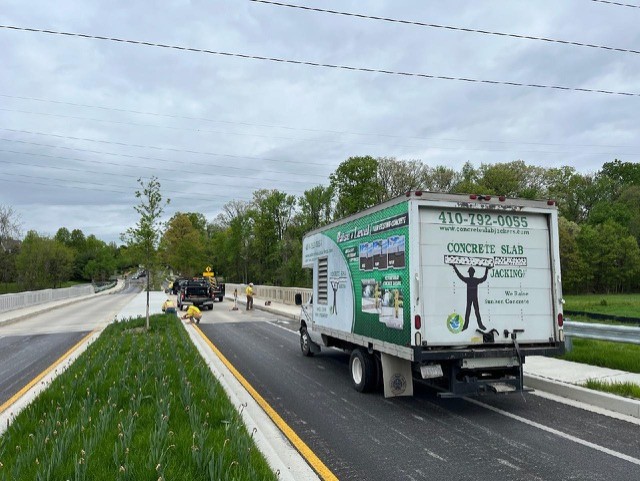 Concrete slab jacking service truck supporting a roadway concrete leveling project with crews working on site in Brambleton, VA.