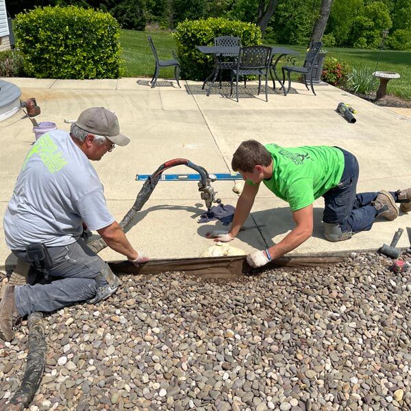 Concrete slab jacking technicians lifting and leveling a sunken residential patio using specialized equipment in Sterling, VA Homes.